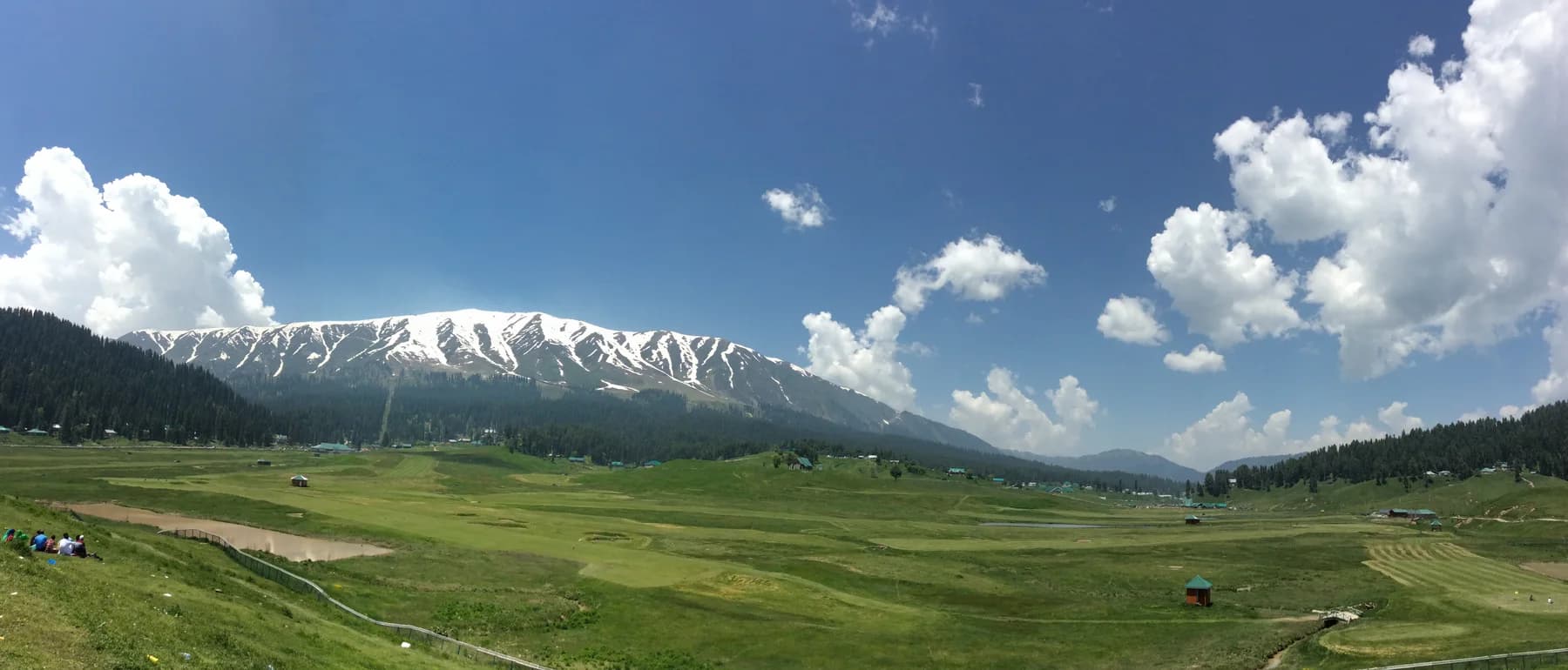 Green meadows below snowy mountains at Gulmarg, photographed 29 May 2016.